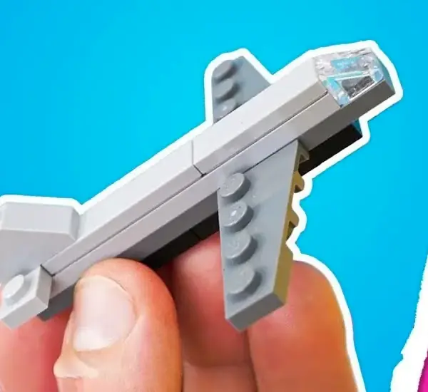 A small grey plane made from bricks, pinched between a thumb and finger